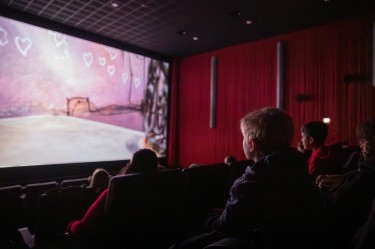 Kinder im KInosaal vor einer hellen Leinwand