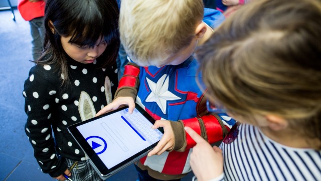 Kinder schauen auf ein Tablet.