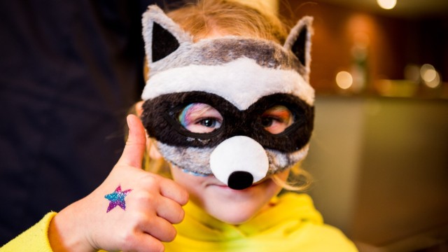 Ein Junge mit Waschbär Maske lächelt in die Kamera.