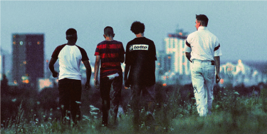 Vier Jungs vor einer Hochhauskulisse