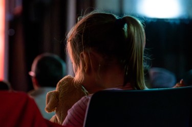 Ein Kind mit Kuscheltier im Arm im Kino.
